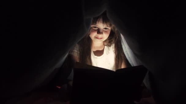 Meisje leesboek onder deken — Stockvideo