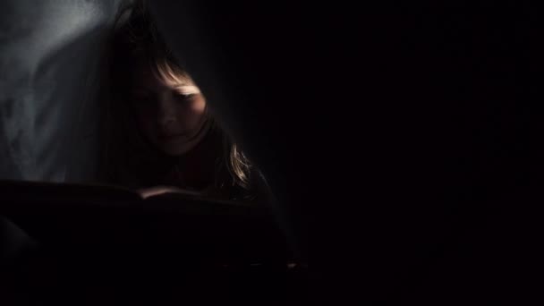 Mädchen liest Buch unter Decke — Stockvideo