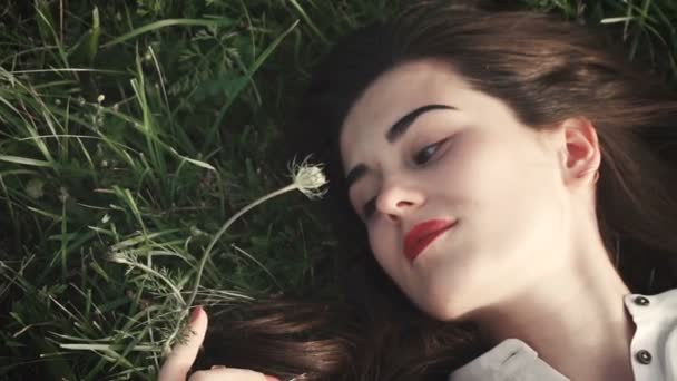 Kaunis tyttö makaa nurmikolla — kuvapankkivideo