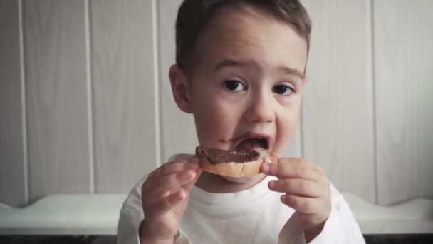 小さな男の子おかしい食べるパンにバター — ストック動画