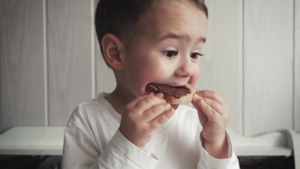 Pequeño niño divertido come pan con mantequilla — Vídeo de stock