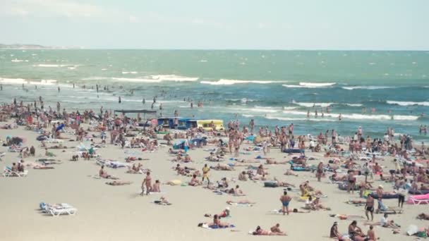 Personas en la playa de la costa del mar — Vídeo de stock