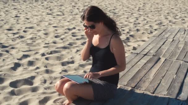 Chica trabajando en la playa con la tableta PC — Vídeos de Stock