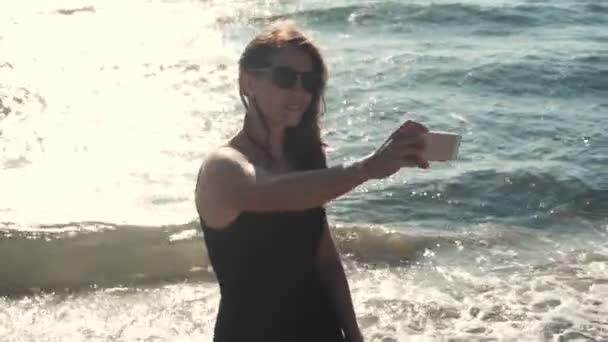 Atraktivní dívka dělá selfie na pobřeží — Stock video
