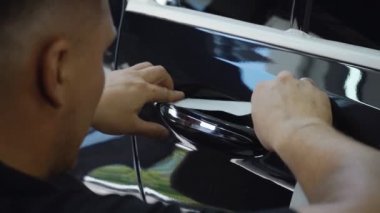 Yetkili tamirci araba kapısının koluna bant yapıştırıyor