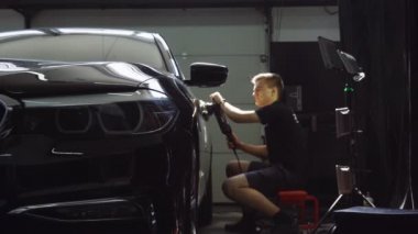 Elektrikli fırçayla araba cilası yapan genç adamın yan görüntüsü