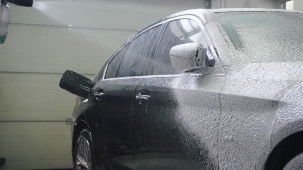Эксперт по автомобилям покрывает темную машину пеной перед мытьем — стоковое видео