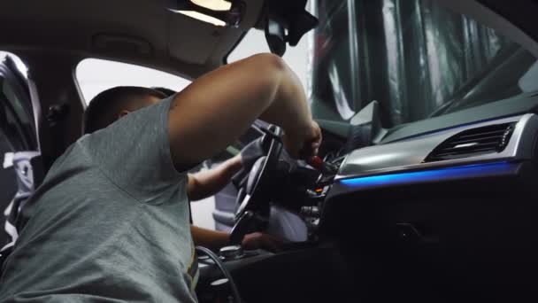 Двоє працівників автосервісу прибирають темну машину всередині — стокове відео