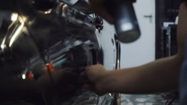 Erkek eli kapalı, araba yüzeyini süngerle temizliyor.