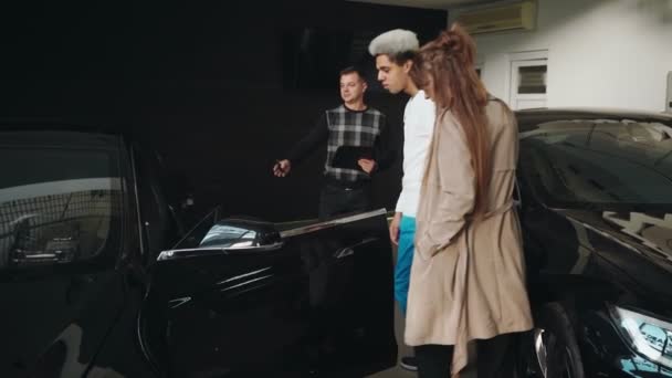 Wieloetniczna rodzina ogląda nowoczesny samochód w salonie samochodowym — Wideo stockowe