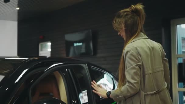Kobieta dotykająca zewnętrznej powierzchni nowego samochodu w salonie — Wideo stockowe