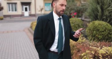 Yürürken akıllı telefon kullanan meşgul bir adam