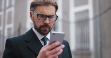 İş adamı sokakta akıllı telefon kullanıyor.