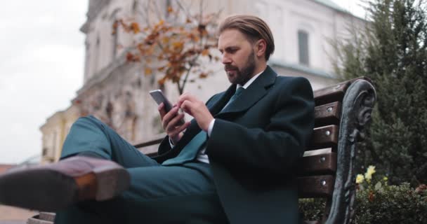 Άνδρας που κάθεται στον πάγκο και χρησιμοποιεί smartphone — Αρχείο Βίντεο