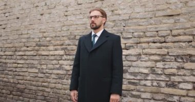 Tuğla duvarın yanında poz veren işadamı