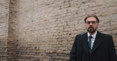 Tuğla duvarın yanında yürüyen korkmuş bir adam.