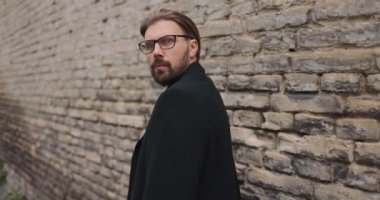 Tuğla duvarın yanına yaklaşan korkmuş bir adam.