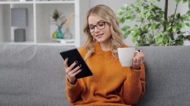 Tablet kullanan ve kahve içen kadın.