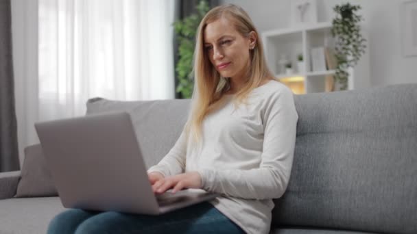 Kvinna avkopplande på soffan med laptop — Stockvideo