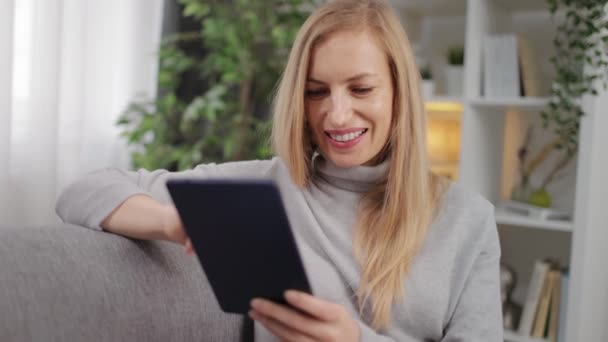 Glückliche Frau mit digitalem Tablet auf der Couch — Stockvideo