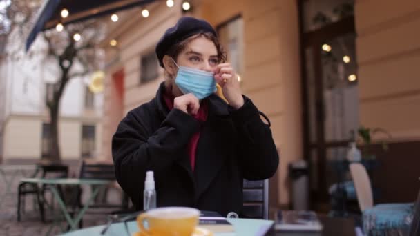 Женщина в маске использует антисептик в кафе — стоковое видео