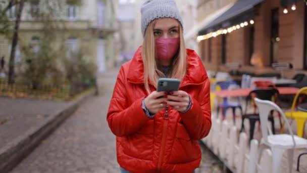 Mujer con máscara usando teléfono inteligente al aire libre — Vídeos de Stock