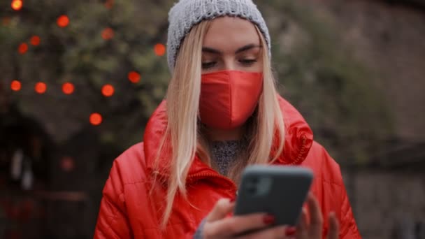 Frau benutzt Handy und trägt Maske auf Straße — Stockvideo