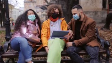 Parkta tablet kullanan maskeli arkadaşlar