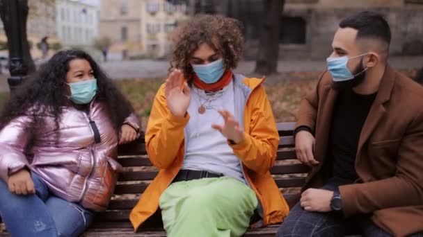 Multiracial people in masks chatting on bench — Stock Video