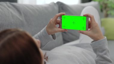 Evde yeşil ekranlı cep telefonu kullanan esmer