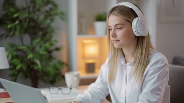 Mujer usando auriculares y portátil mientras estudia — Vídeos de Stock