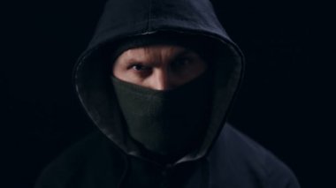 Siyah maskeli ve başlıklı ciddi bir adamın portresi.