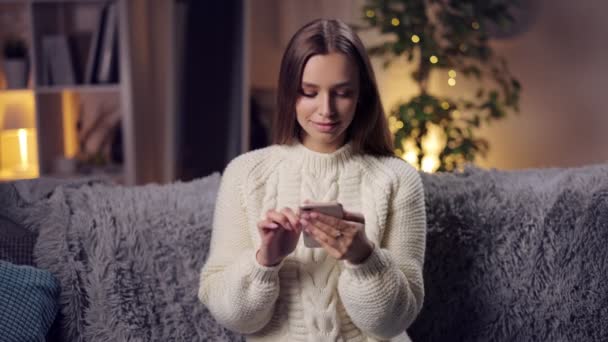 Uśmiechnięta brunetka korzystająca ze smartfona w domu — Wideo stockowe