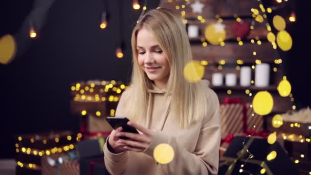 Femme utilisant un smartphone avec des guirlandes lumineuses autour — Video