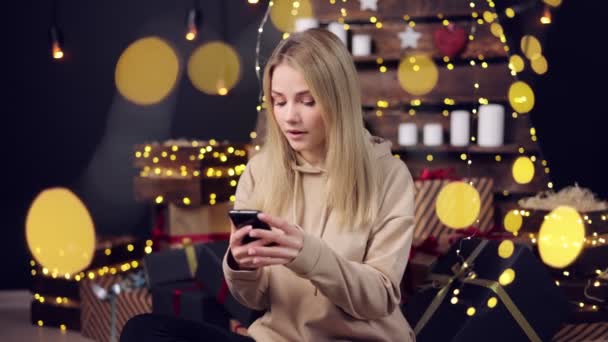 Жінка використовує мобільний з різдвяним прикрасою на фоні — стокове відео