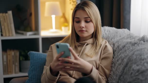 Жінка друкує повідомлення на смартфоні вдома — стокове відео