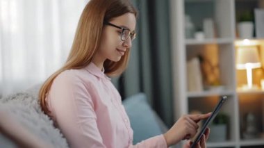 Kanepede oturan ve tablet kullanan kadın.