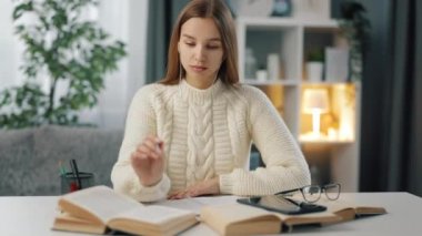 Kulaklıklı kadın masada ders çalışıyor.