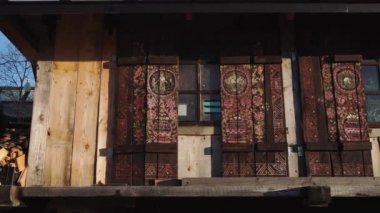 Karlı ormanın ortasında, ahşap evin yanında oturan bir kadın.
