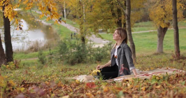 Atrakcyjna kobieta relaksująca się w jesiennym parku — Wideo stockowe