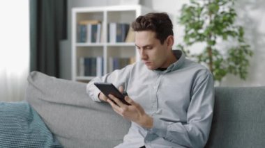Oturma odasında dijital tablet kullanan adam