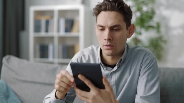 Enttäuschter Mann mit Tablet im Wohnzimmer — Stockvideo