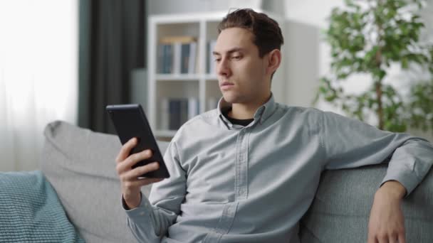Uvolněný muž sedící na pohovce s tabletem — Stock video
