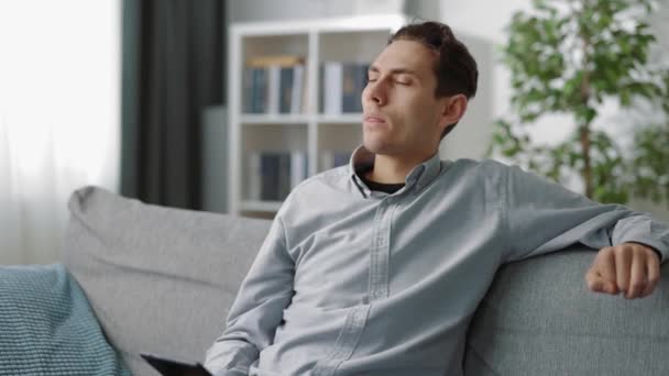 Nachdenklicher Mann sitzt mit Tablet auf Couch — Stockvideo