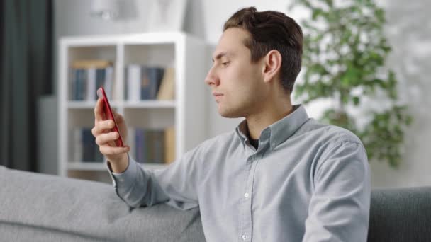 Glücklicher Mann mit Smartphone auf Couch — Stockvideo