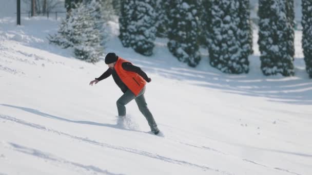 男は大雪の上で丘の上に上がる — ストック動画