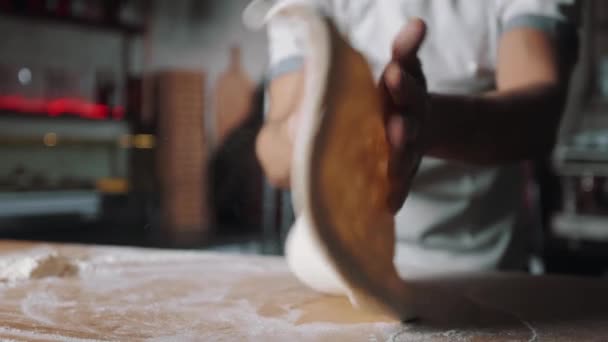 Primer plano de la masa giratoria pizzaiolo en las manos — Vídeo de stock