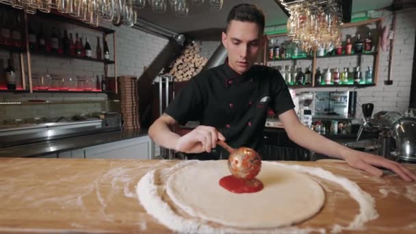 Szef kuchni nakładający sos pomidorowy na ciasto pizzowe — Wideo stockowe