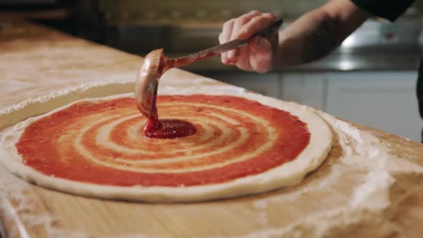 Närbild av manliga händer sprider sås på pizza deg — Stockvideo