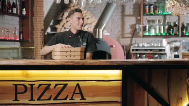 Smiling pizzaiolo giving three pizza boxes to male client — Stock Video